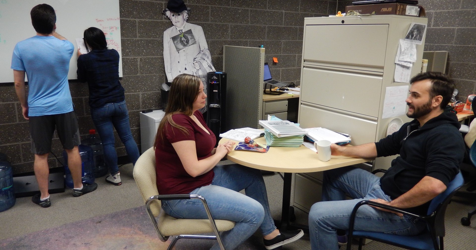 Students confer and work together in the graduate student office